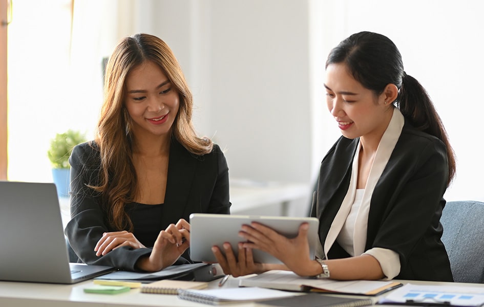 Two businesswomen discussing digital strategies on tablet